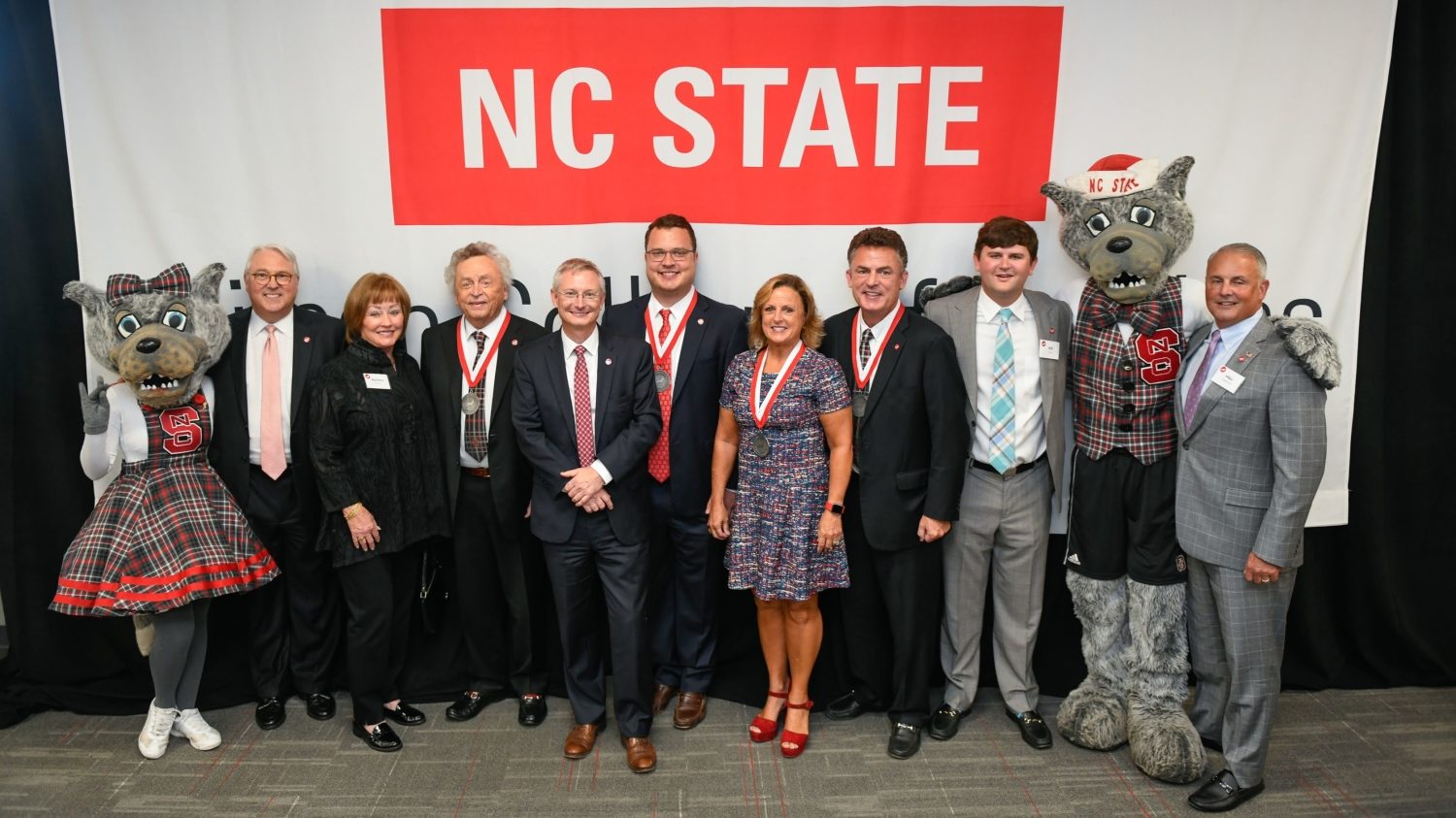 Mr. and Mrs. Wuf, Chancellor Woodson, Dean Hinks and the Wilson family in front of the new Wilson College of Textiles sign